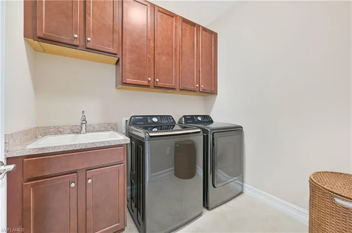 Washroom featuring cabinet space, independent washer and dryer, and light tile patterned floors