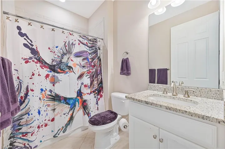 Bathroom featuring a shower with shower curtain, vanity, and light tile patterned floors