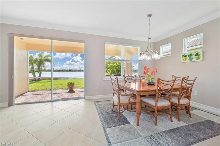 Dining area with ornamental molding, light tile patterned floors, a water view, and a chandelier
