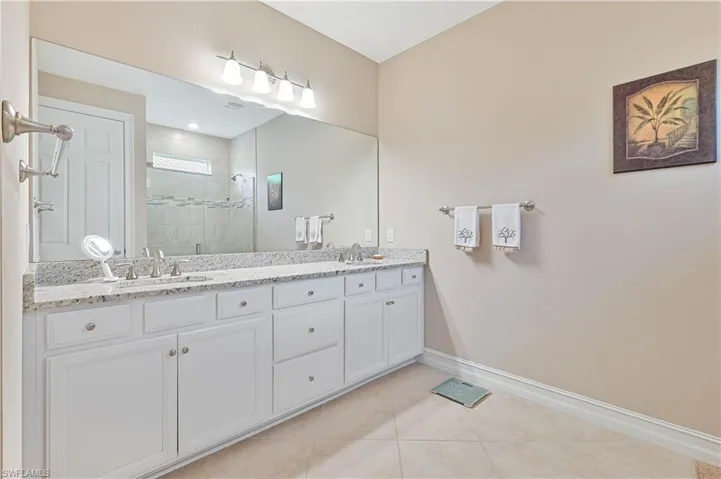 Bathroom with a stall shower, double vanity, and light tile patterned floors