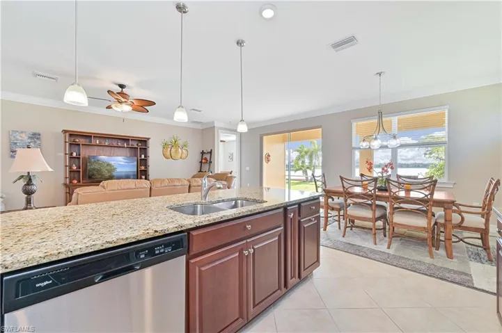 Kitchen with light stone counters, dishwasher, pendant lighting, light tile patterned flooring, and ornamental molding