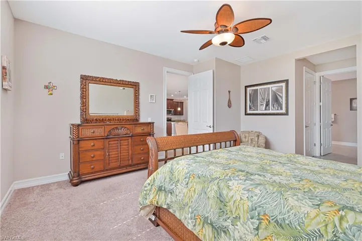 Bedroom with light colored carpet, a ceiling fan, and connected bathroom