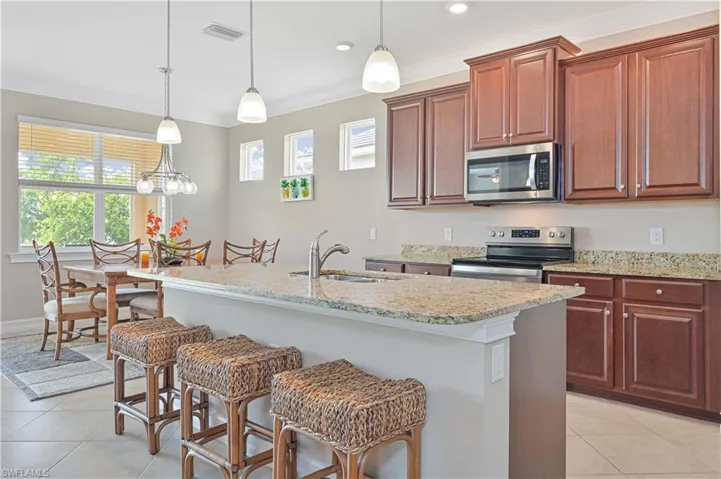 Kitchen with a breakfast bar area, light tile patterned floors, decorative light fixtures, crown molding, and recessed lighting
