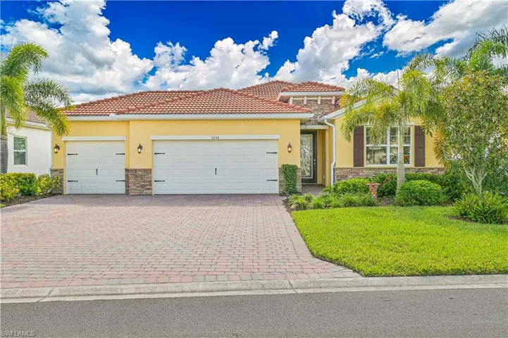 Mediterranean / spanish-style house with stone siding, a front yard, stucco siding, and decorative driveway