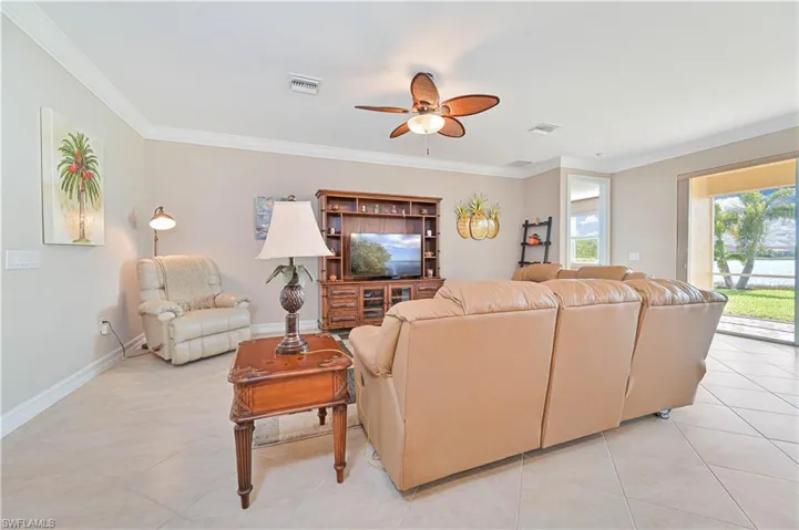 Living area with ornamental molding, ceiling fan, and light tile patterned floors