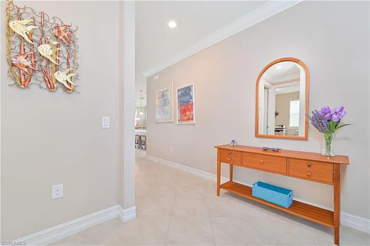 Hall with light tile patterned floors, ornamental molding, and recessed lighting