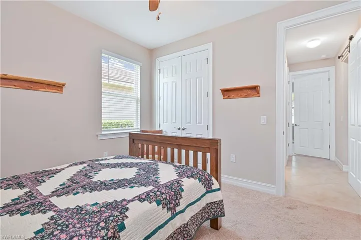 Bedroom featuring light colored carpet, ceiling fan, a closet, and a barn door