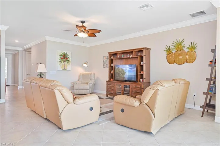 Living area featuring ornamental molding, a ceiling fan, and light tile patterned floors