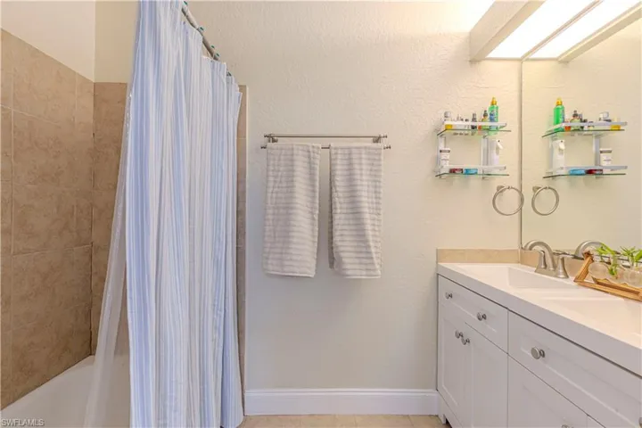 Bathroom with double vanity and shower / tub combo with curtain