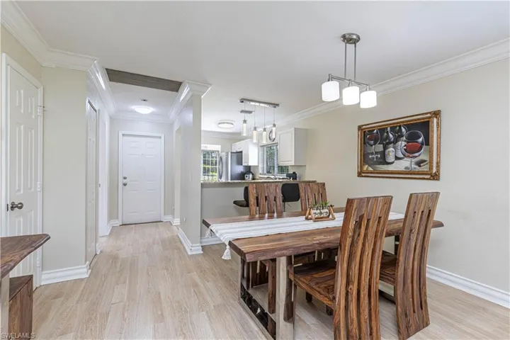 Dining space with ornamental molding and light wood-style flooring