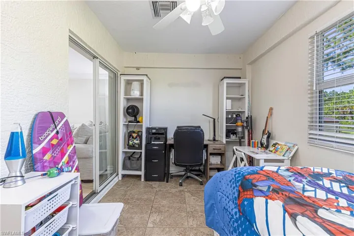 Bedroom featuring tile patterned flooring, an office area, and a ceiling fan