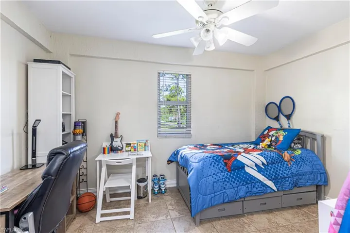 Tiled bedroom with an office area and a ceiling fan