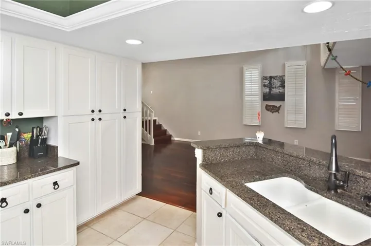 Kitchen with white cabinets, dark stone countertops, light tile patterned flooring, and recessed lighting