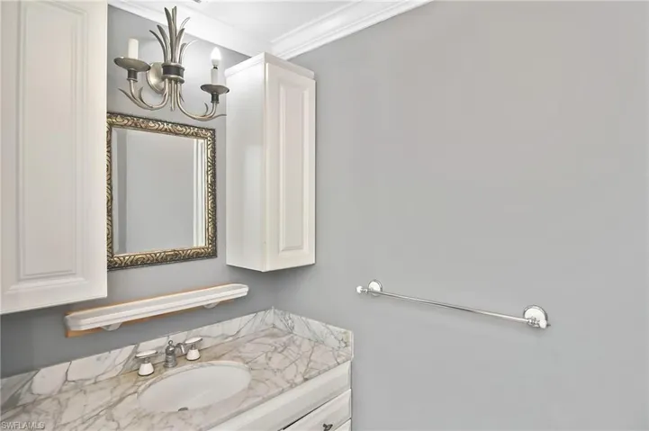 Bathroom with vanity, ornamental molding, and hanging lights