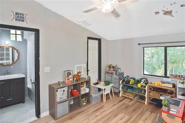 Recreation room with vaulted ceiling, light wood-type flooring, and a ceiling fan