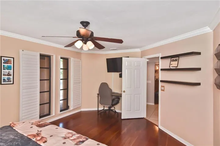 Bedroom featuring ornamental molding, wood finished floors, ceiling fan, and an office area
