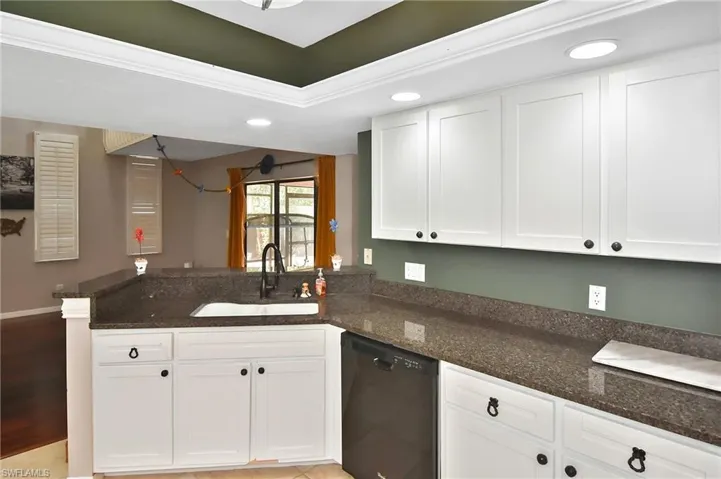 Kitchen featuring a peninsula, dark stone countertops, white cabinets, black dishwasher, and recessed lighting