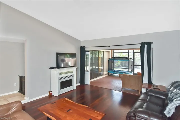 Living room with wood finished floors, a fireplace, and lofted ceiling