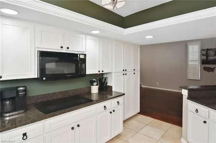 Kitchen featuring black appliances, recessed lighting, white cabinetry, dark stone countertops, and light tile patterned floors