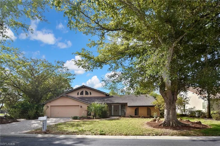 View of front of home featuring a tiled roof, stucco siding, a front lawn, driveway, and an attached garage
