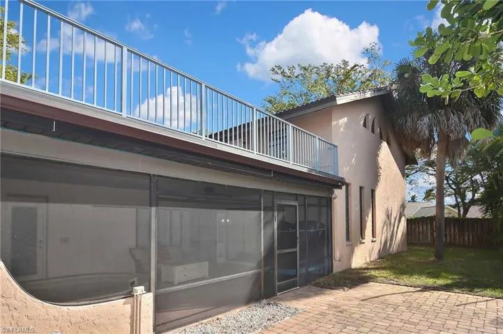 Back of house with stucco siding, a sunroom, a patio area, and a balcony