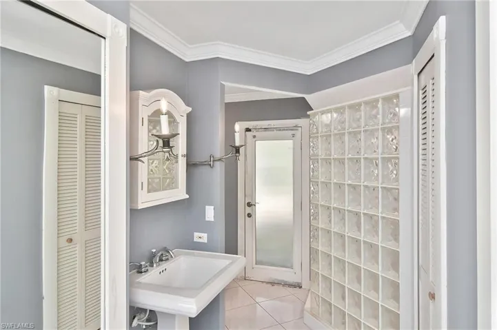 Bathroom with a closet, crown molding, and light tile patterned flooring