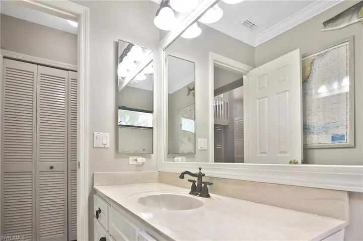 Bathroom featuring a closet, vanity, and crown molding