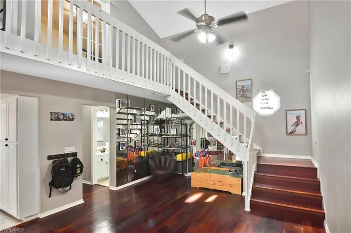 Stairway featuring wood-type flooring, a high ceiling, and ceiling fan