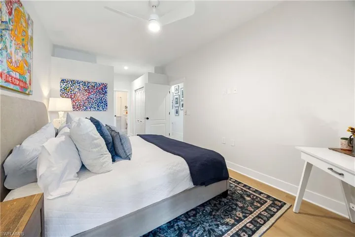 Bedroom with ceiling fan, walk -in closte, wood finished floors, and baseboards