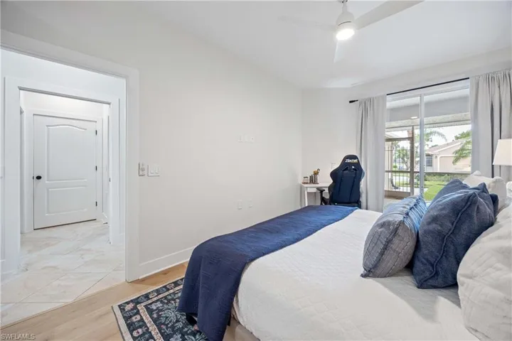Bedroom with baseboards, light wood-style flooring, a ceiling fan, and access to exterior