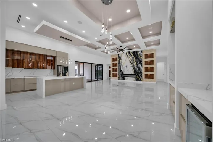 Unfurnished living room with coffered ceiling, light marble finish flooring, wine cooler, recessed lighting, and beamed ceiling
