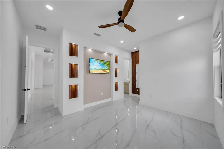 Unfurnished bedroom featuring connected bathroom, light marble finish flooring, ceiling fan, and recessed lighting