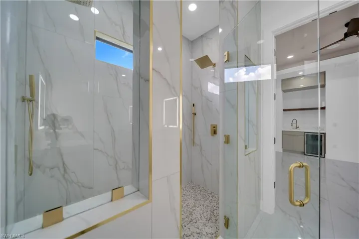 Bathroom with a marble finish shower, recessed lighting, and beverage cooler