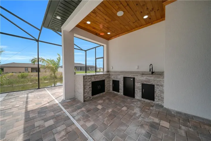View of patio with a sunroom, an outdoor kitchen, a lanai, and a water view