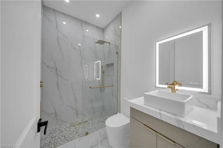 Full bathroom featuring marble tiled floors, a marble finish shower, vanity, and recessed lighting
