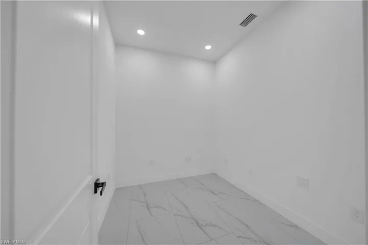 Empty room featuring light marble finish floors and recessed lighting