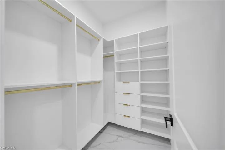Walk in closet featuring light marble finish floors