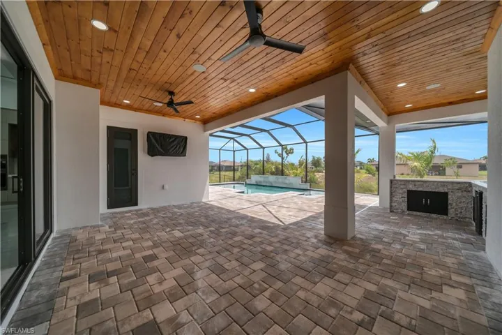View of patio / terrace featuring ceiling fan, a sunroom, a lanai, an outdoor pool, and a jacuzzi