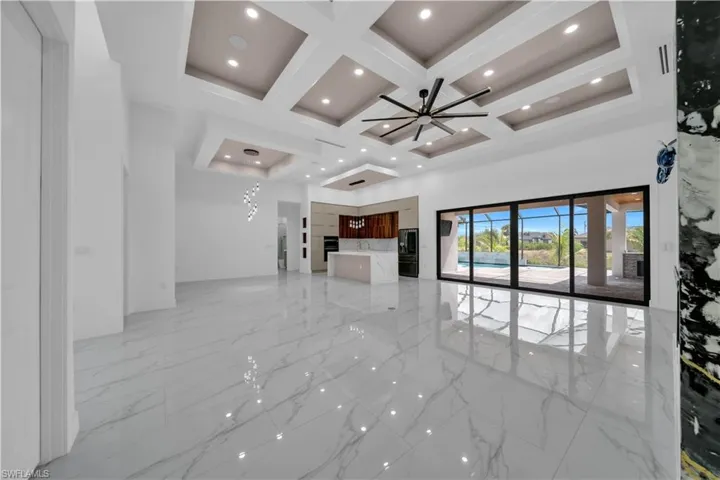 Unfurnished living room featuring light marble finish flooring, coffered ceiling, a towering ceiling, beam ceiling, and recessed lighting