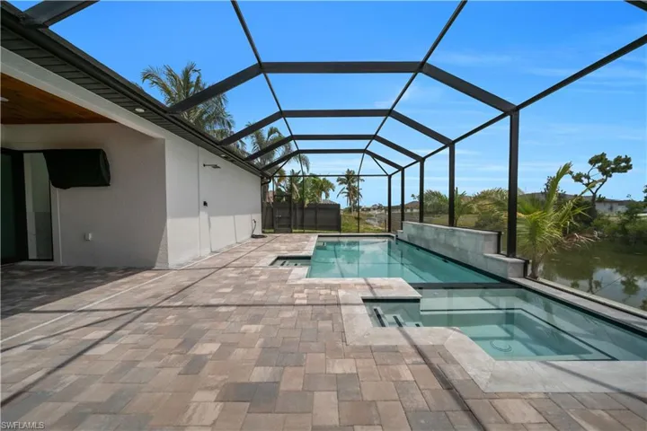 View of pool with a sunroom, glass enclosure, a patio, and a pool with connected hot tub