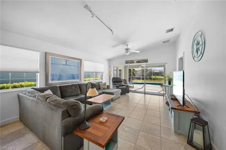 Living area featuring ceiling fan, track lighting, a sunroom, lofted ceiling, and light tile patterned flooring