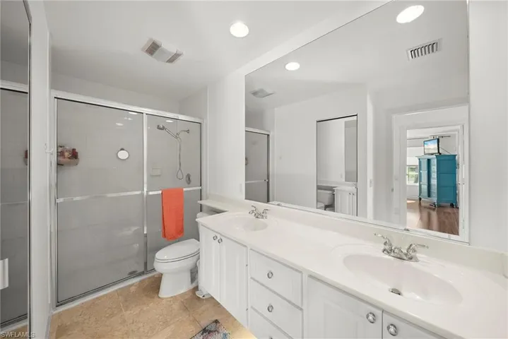 Full bathroom featuring double vanity, a stall shower, and recessed lighting