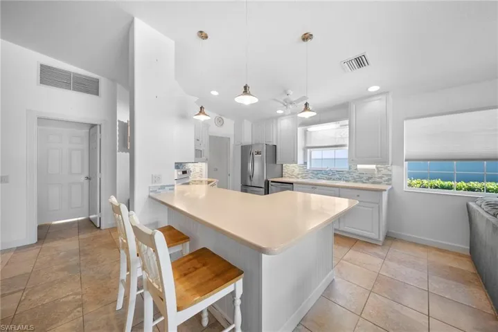 Kitchen with light countertops, white cabinets, a breakfast bar area, and decorative backsplash