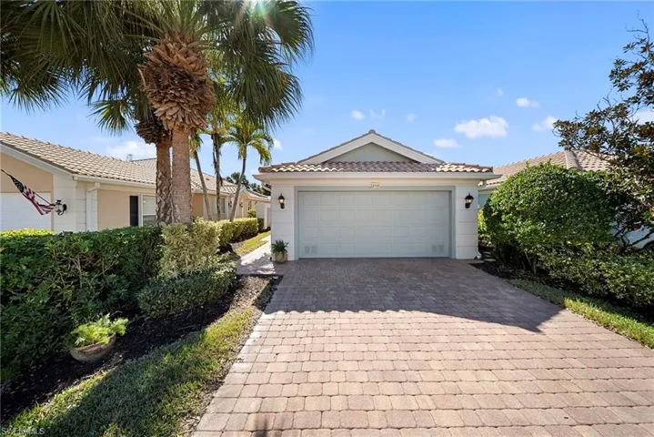 View of front of property featuring a garage, decorative driveway, a tile roof, and stucco siding