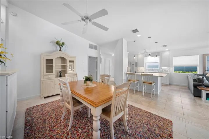 Dining space featuring a ceiling fan, light tile patterned floors, and lofted ceiling