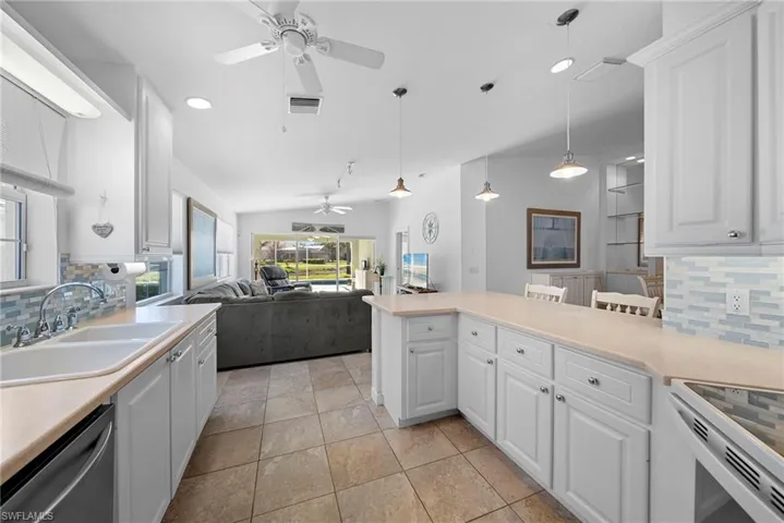 Kitchen featuring decorative backsplash, white cabinetry, and lofted ceiling