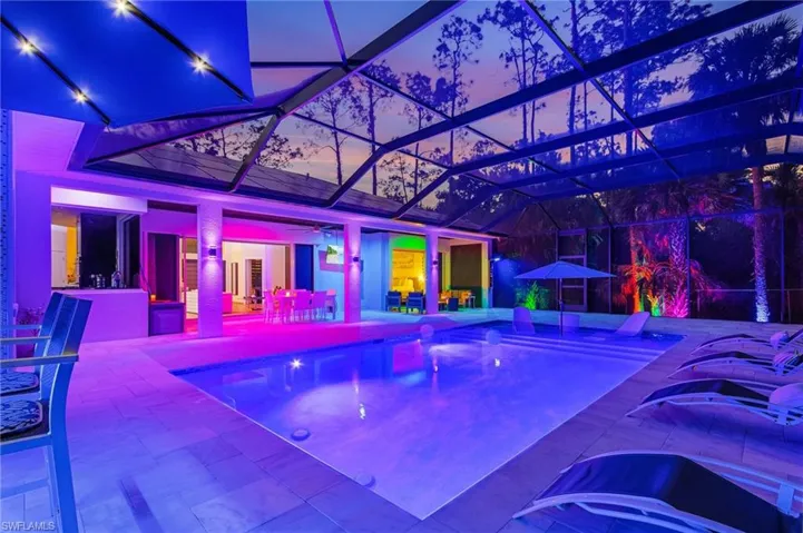 Pool at dusk with a patio area and glass enclosure