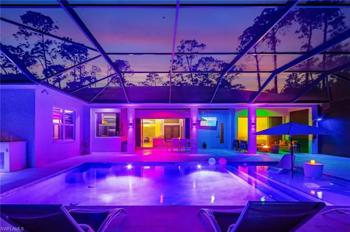 Pool at dusk featuring a patio area and glass enclosure