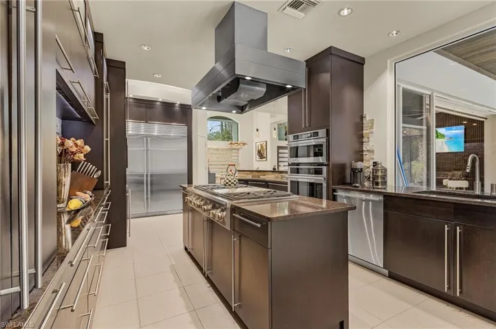Kitchen with island range hood, stainless steel appliances, a kitchen island, sink, and modern dark brown cabinets
