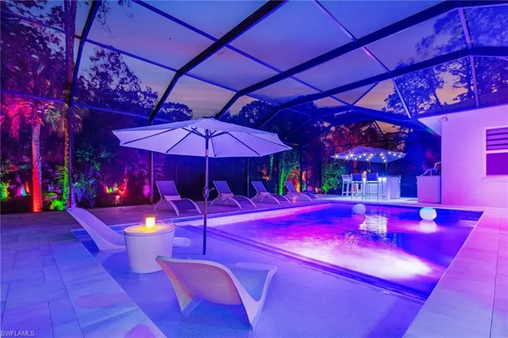 Pool at dusk featuring a lanai and a patio area